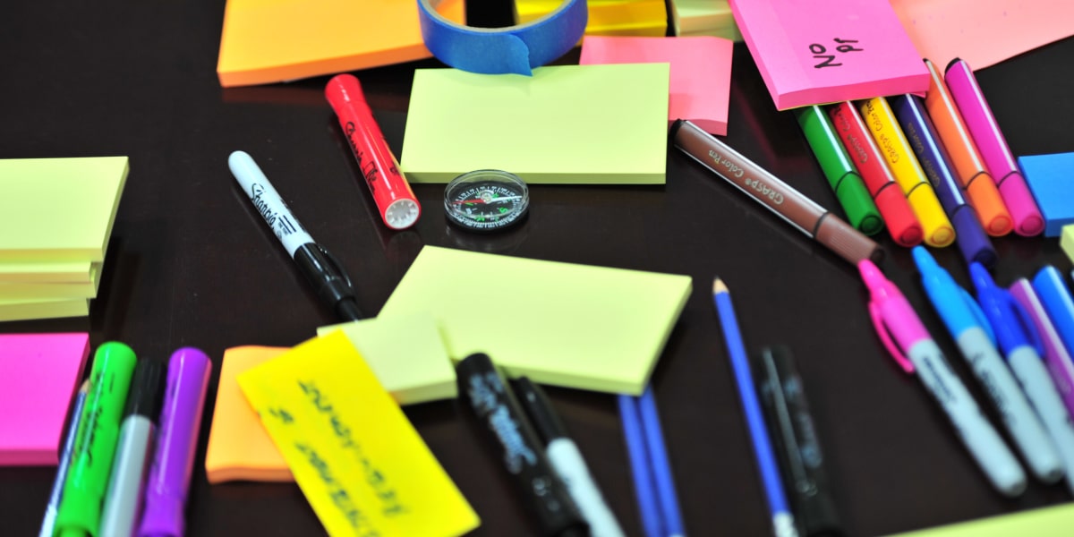 A UX designer's desk covered in colorful sticky notes, markers, and pens