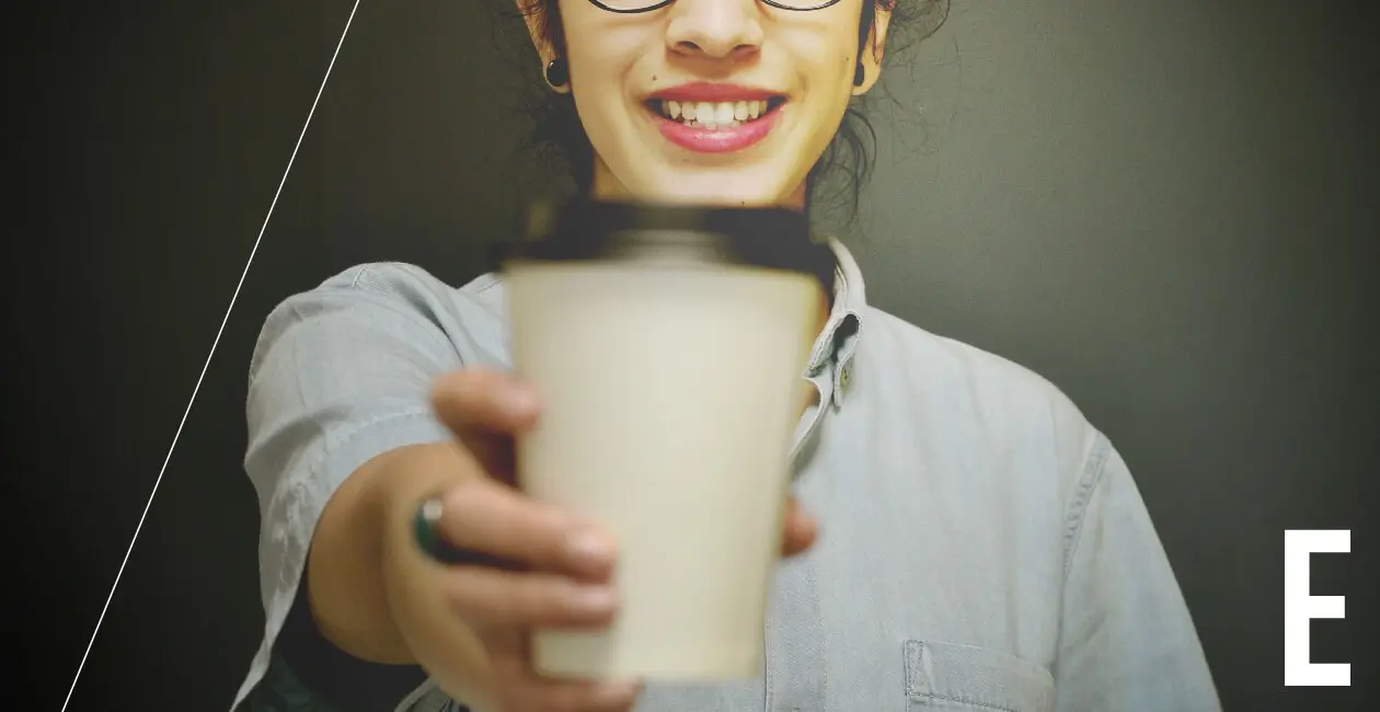 A person offering a cup of coffee toward the camera