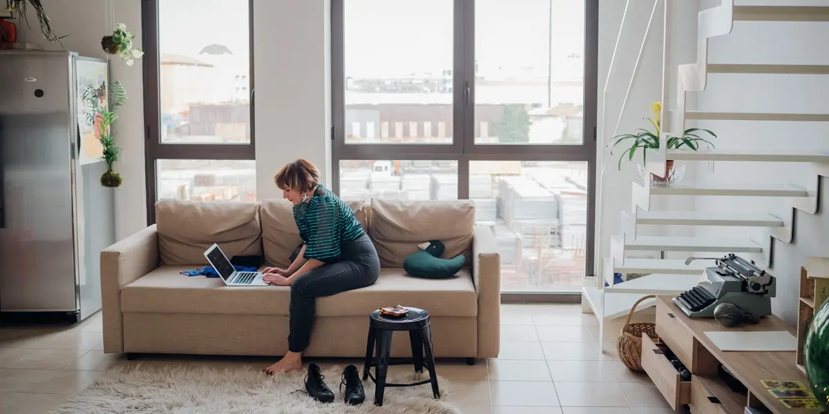 An aspiring UI designer sitting on a sofa, working on a laptop