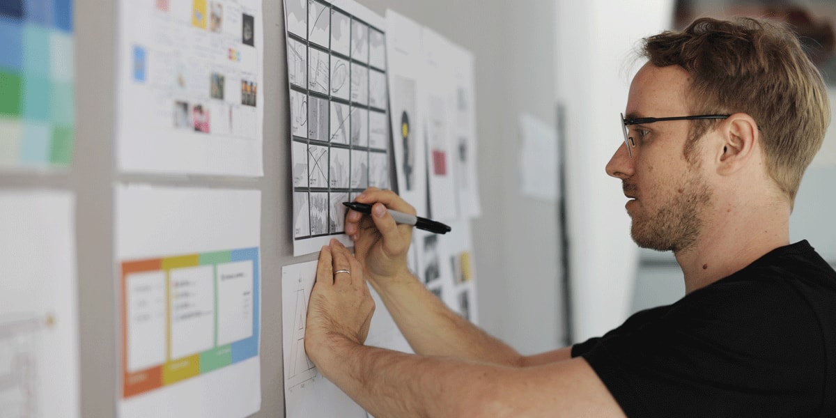 A designer in side profile, writing on a whiteboard
