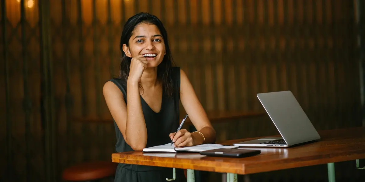 A data analyst writing in a notebook, smiling