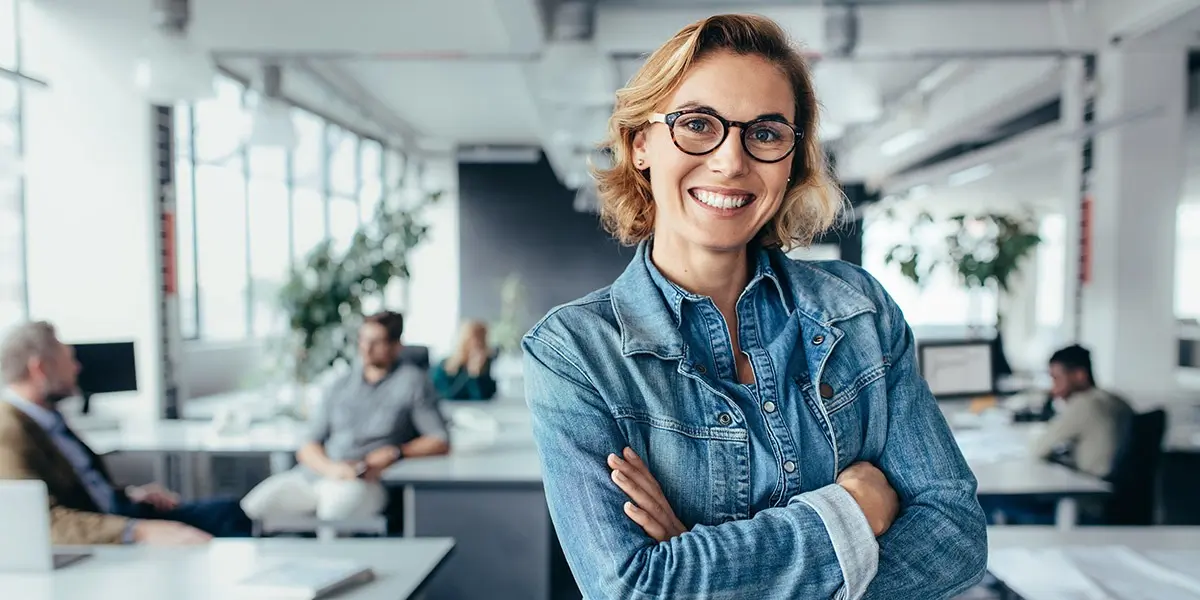 A UX designer standing in an office, smiling at the camera