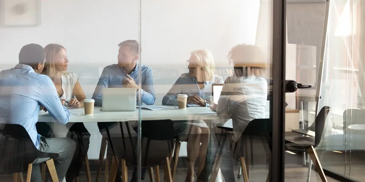 A group of data analysts sitting in a glass meeting room