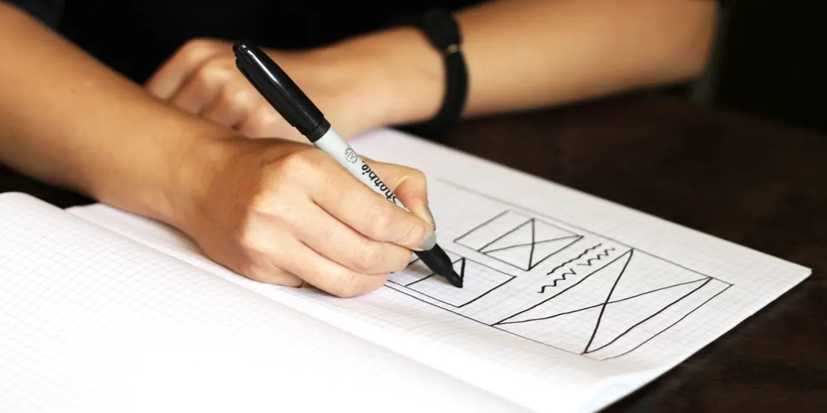 UX designer's hands drawing a simple wireframe on paper