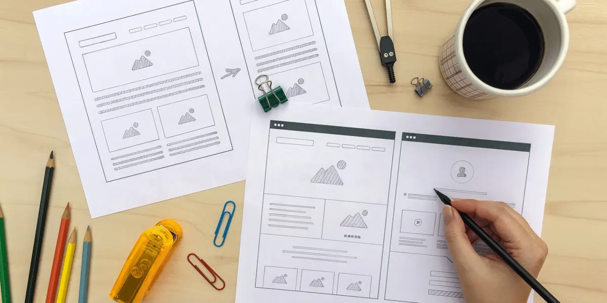 A designer's hands, adding detail to a paper wireframe