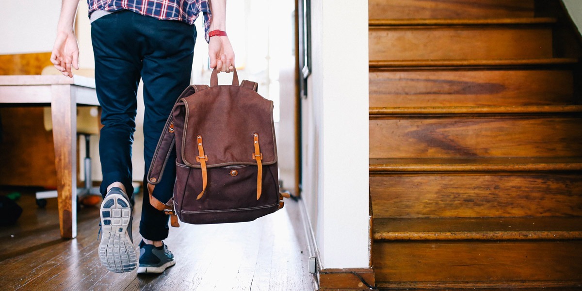 A remote UX designer walking with a packed bag, ready to travel