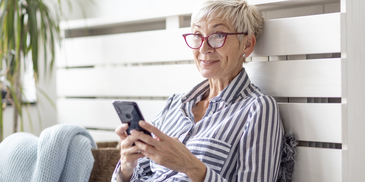 A woman sitting on a bench, working on her phone