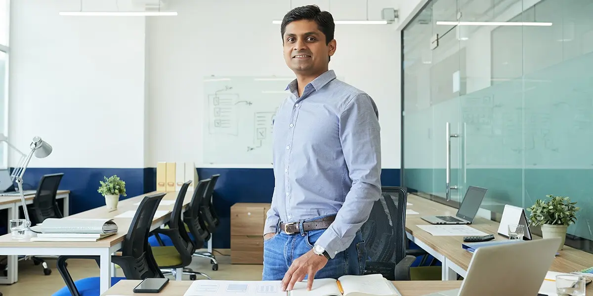 A UX designer standing in a large meeting room, smiling at the camera