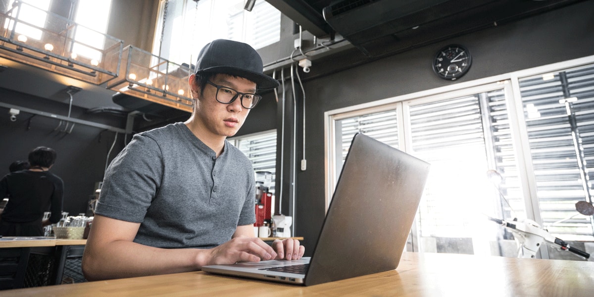 A UX designer sitting at a desk, browsing portfolios on his laptop