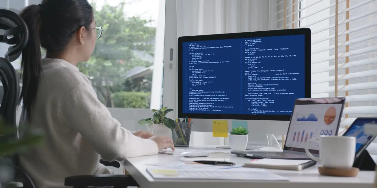 A data engineer in side profile, looking at code on a desktop screen
