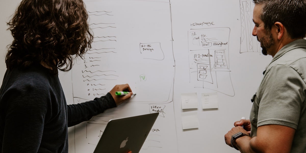 Two designers working at a whiteboard during a UX design interview