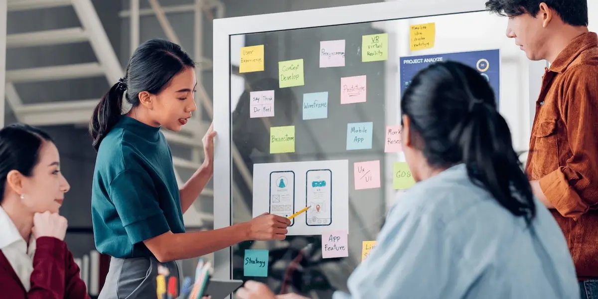 A ui designer shows others her plan on a board