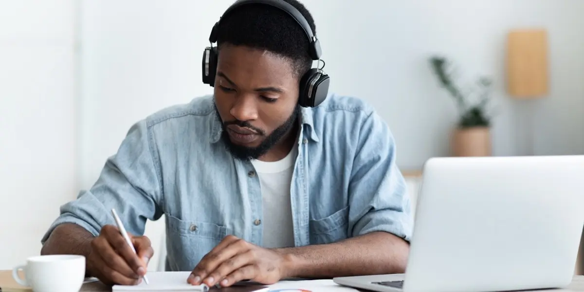 A UX design student working at a desk, wearing earphones