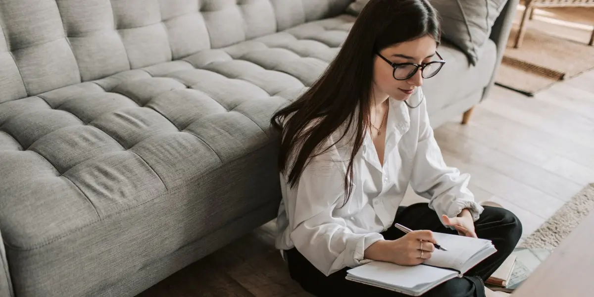 An aspiring designer sitting on the floor of her living room, considering the pros and cons of UX bootcamps