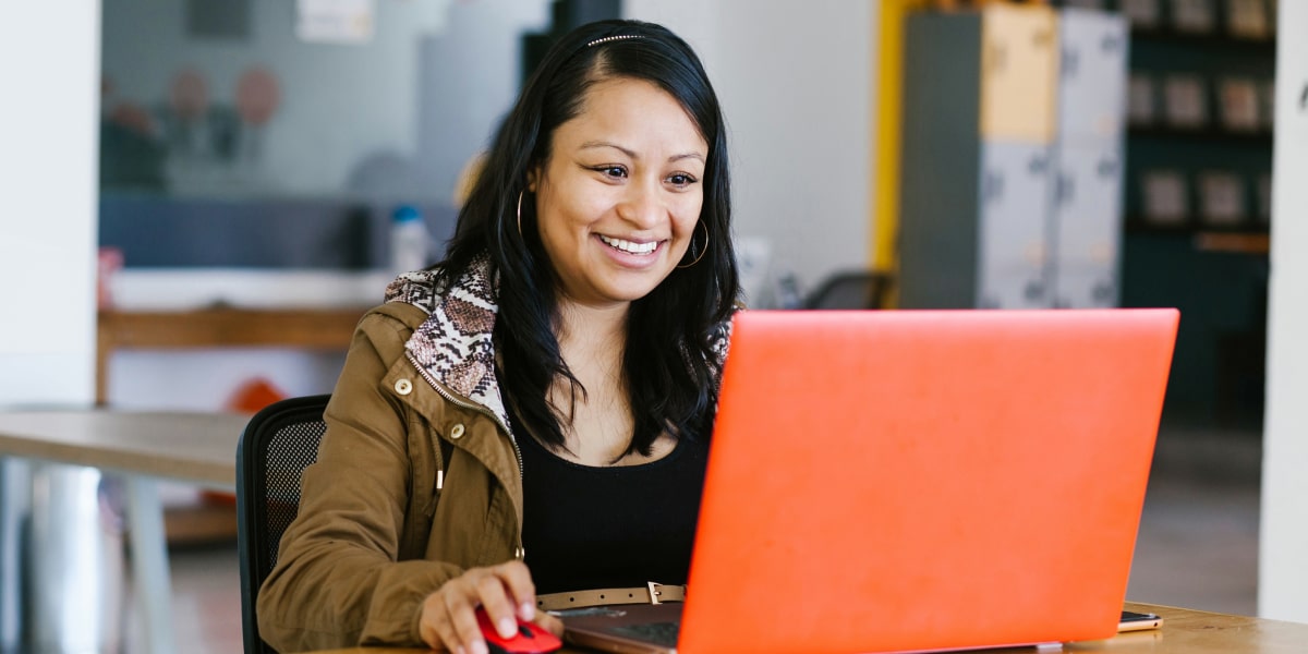 A social media specialist working on a laptop, smiling