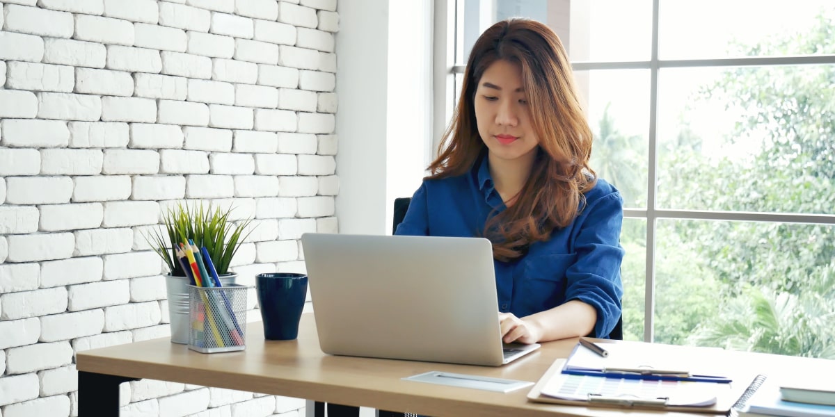 An aspiring marketer sitting at a desk, creating their marketing portfolio website on a laptop