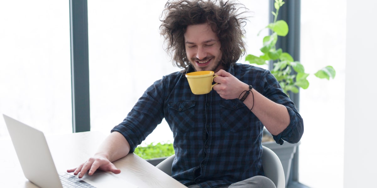 A digital marketing specialist working from home, sipping a cup of coffee sitting at a desk