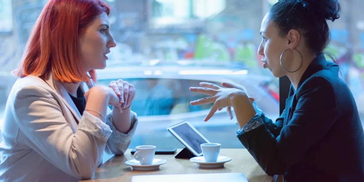 Two people sitting in a cafe, discussing the importance of a marketing portfolio