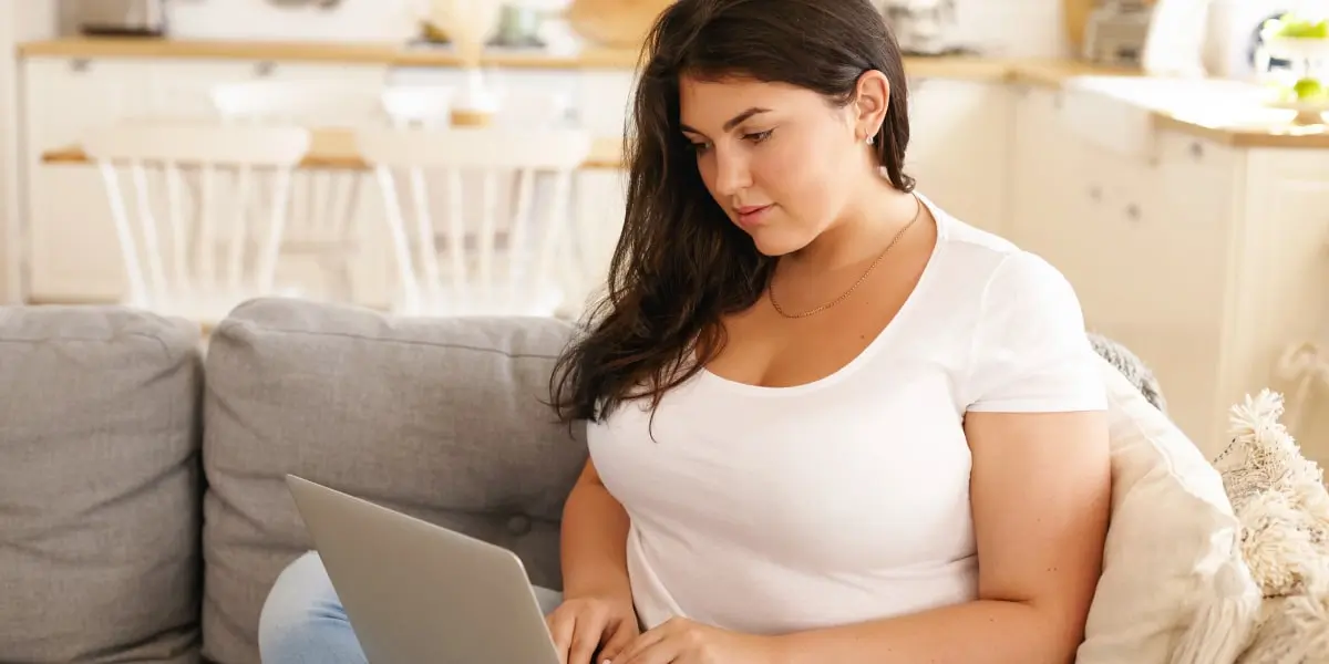 A person sitting on a sofa, using a laptop to create their marketing resume