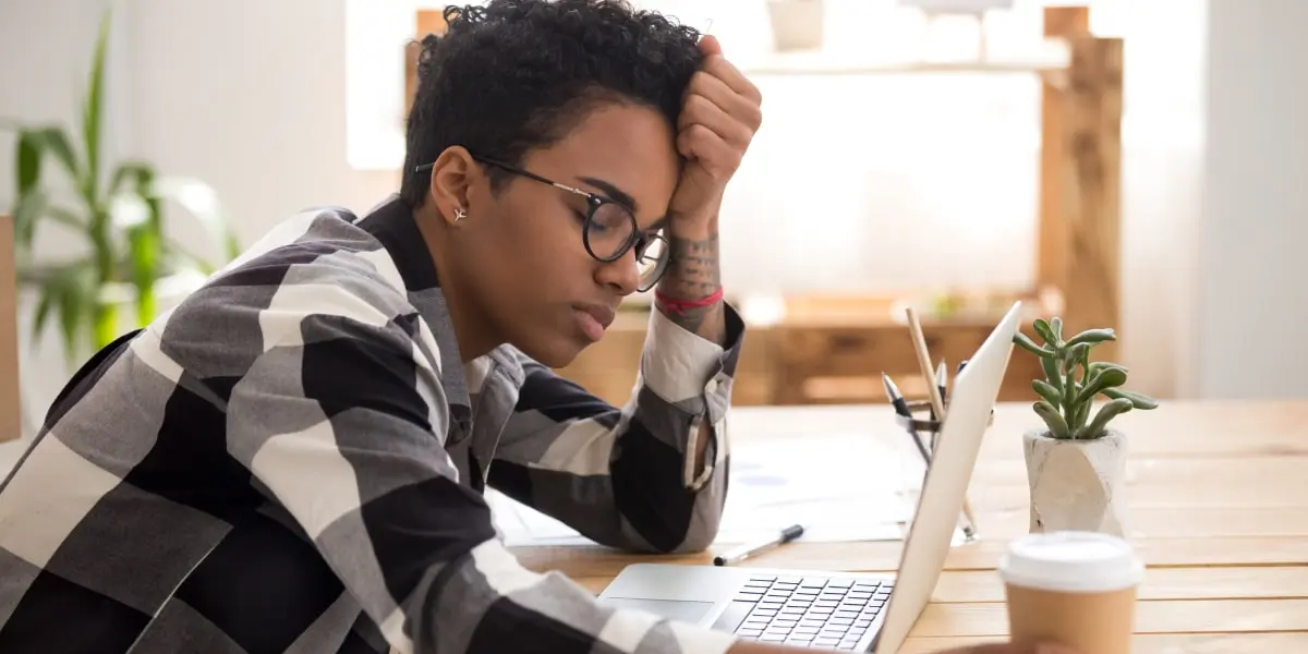 A person in side profile, sitting at a desk, looking through their marketing resume on a laptop