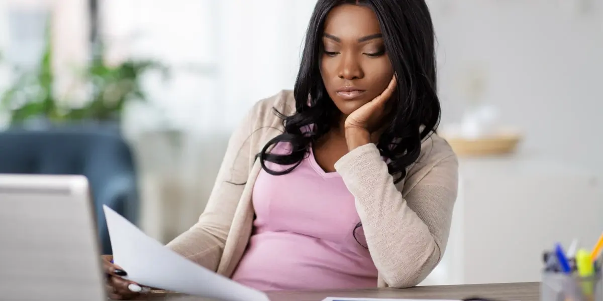 A social media manager sitting at a desk, looking at a document, chin resting on hand