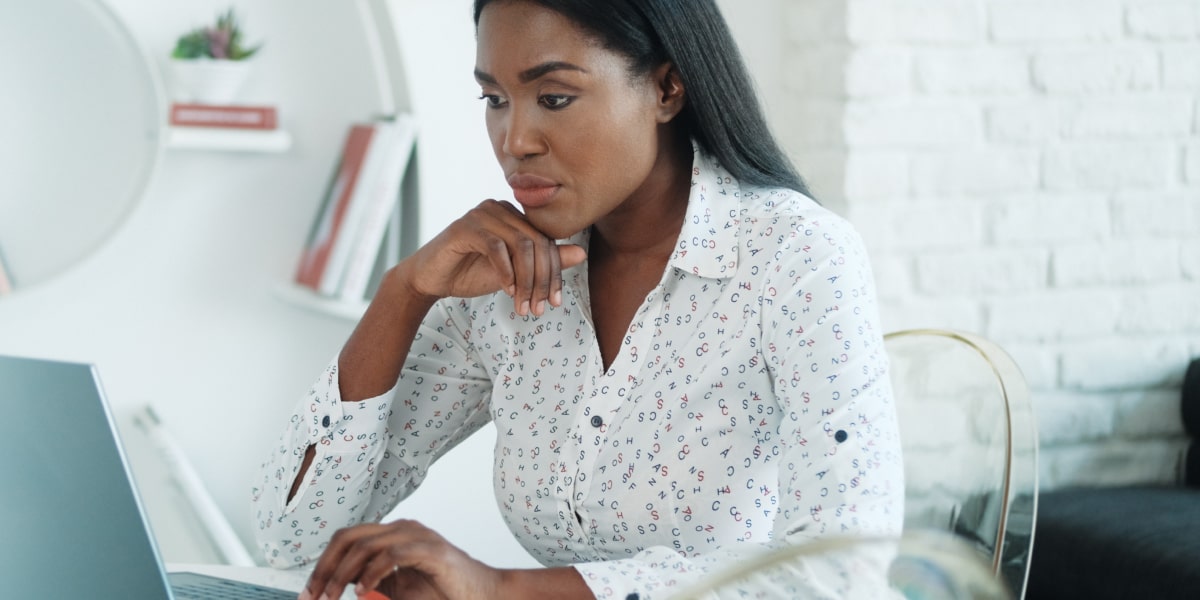 A person sitting in side profile looking at a laptop, researching how to devise an omnichannel marketing strategy