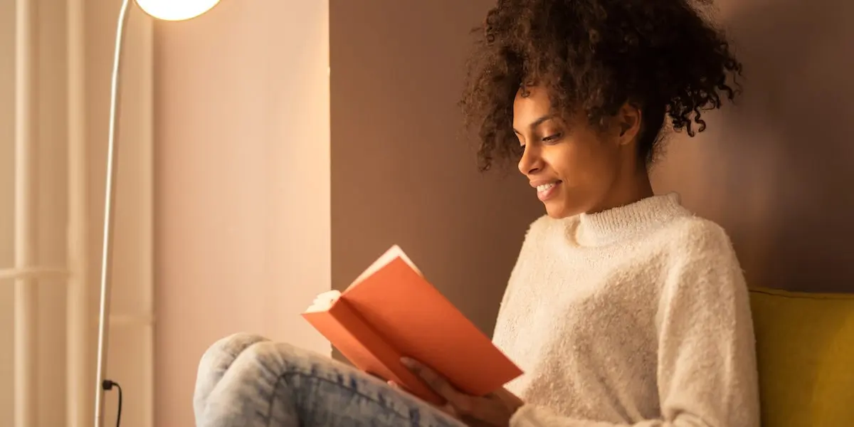 Person reading one of their data books on the sofa under a standing lamp