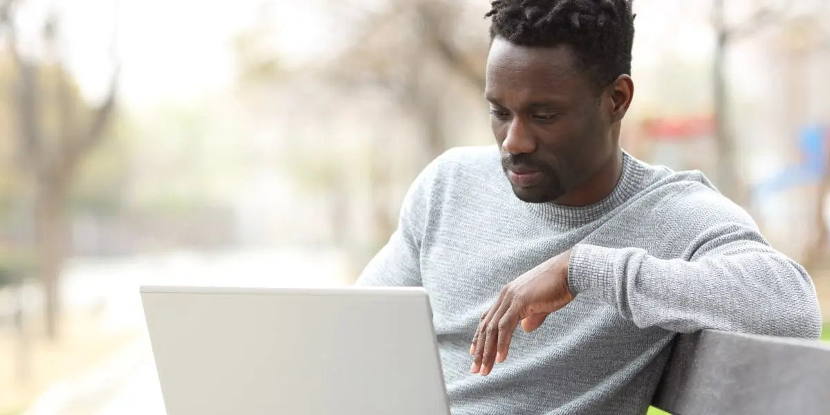 A social media manager sitting on a bench outside, working on a laptop