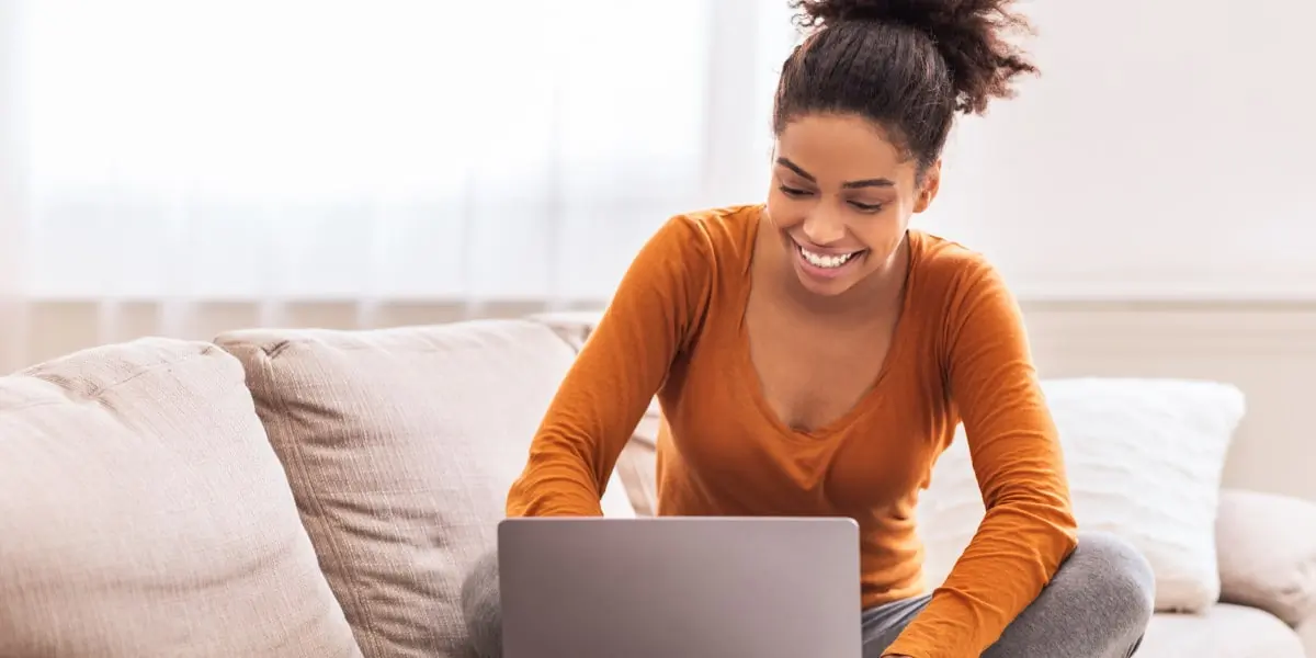 A freelance digital marketing specialist sitting on a sofa, working on a laptop