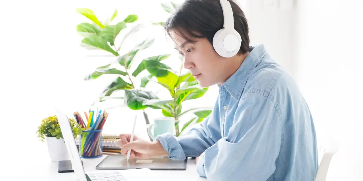 An aspiring digital marketer sitting at a desk, wearing headphones, learning about the key marketing metrics