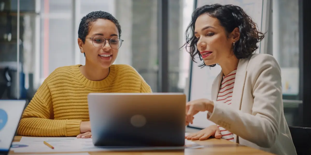 Image of a VP of Product discussing the product manager career path with her colleague on a laptop in an office.