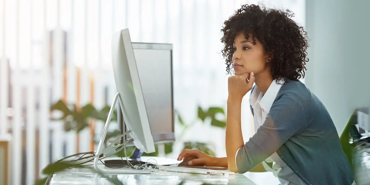 A woman sits at a computer taking a product management course online.