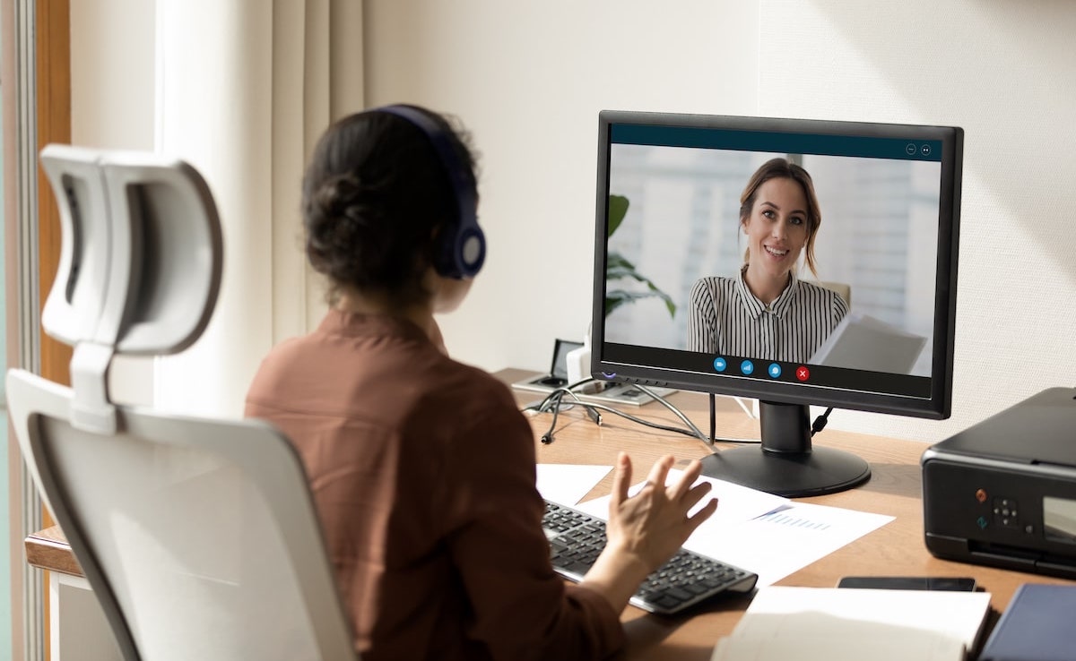 A woman sits in her home office being asked product manager interview questions in a virtual interview.