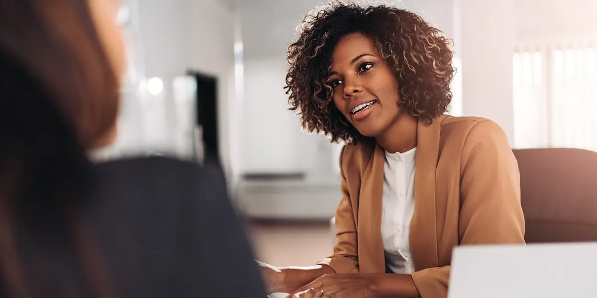 A woman sits being asked product manager interview questions in an office.