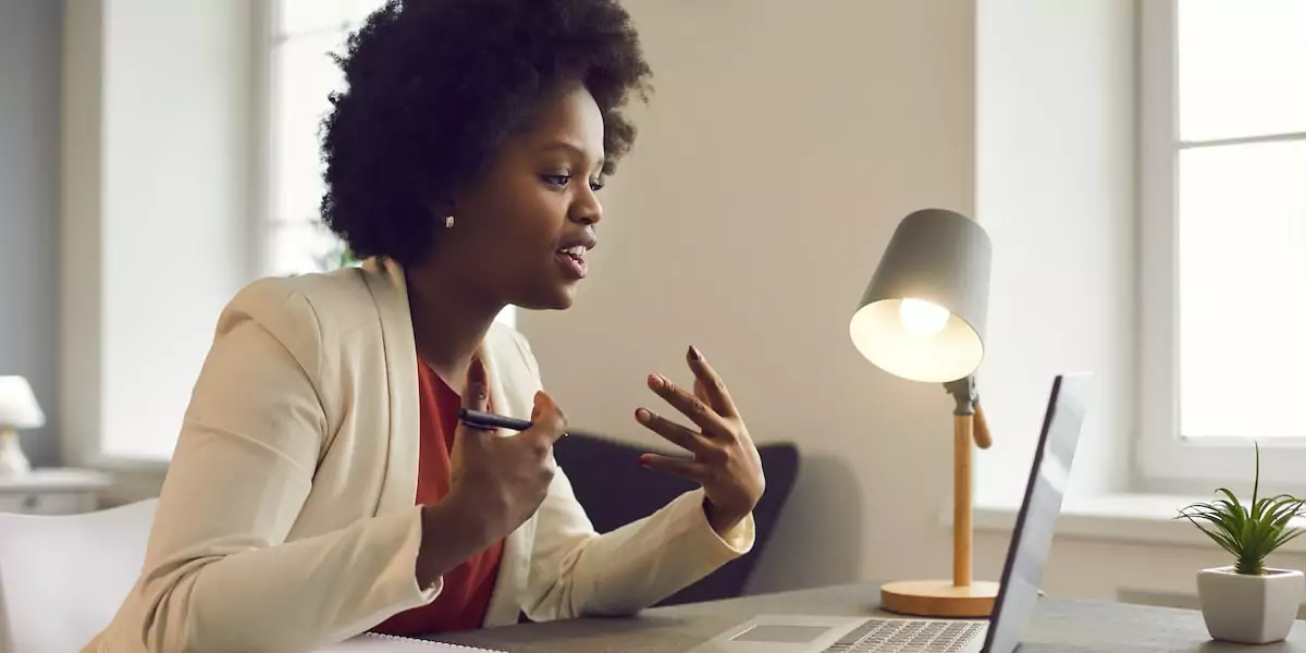 A product manager with an afro wondering what is a user flow discussing with her colleagues on a laptop.