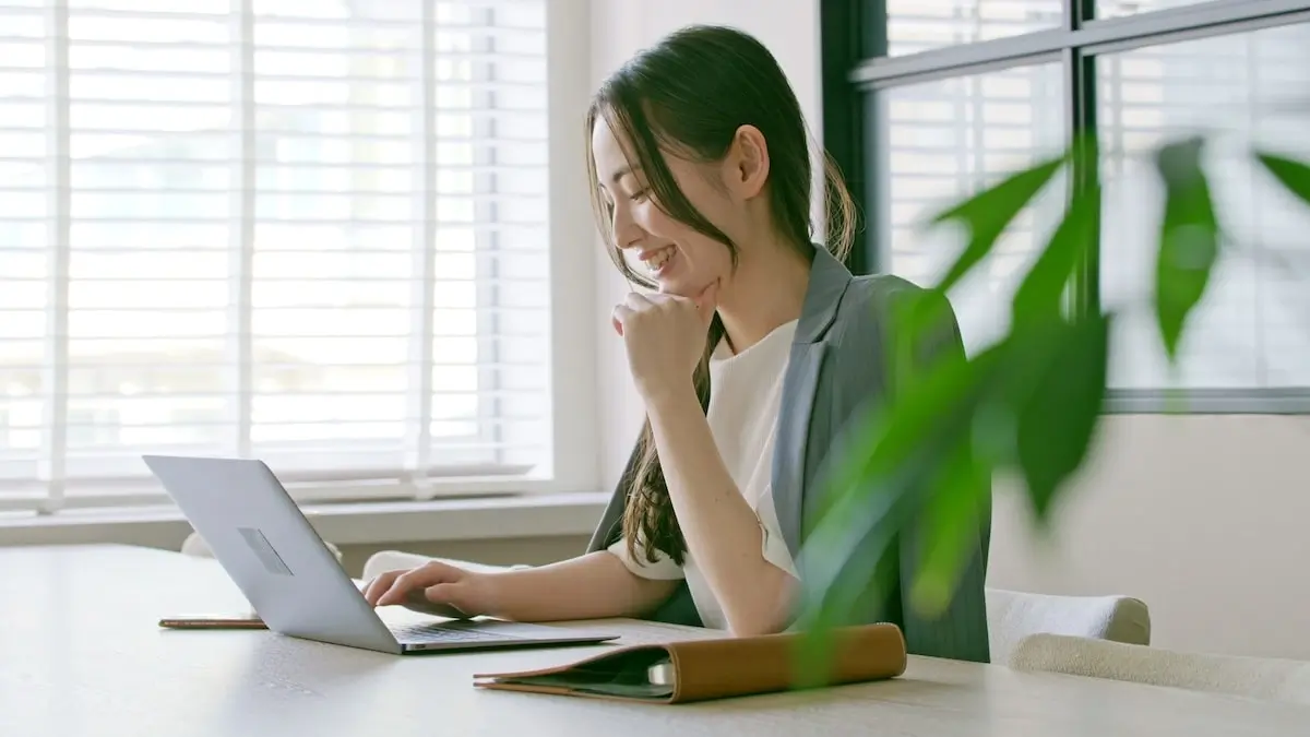 A female web developer sits at her laptop smiling during a remote technical interview.