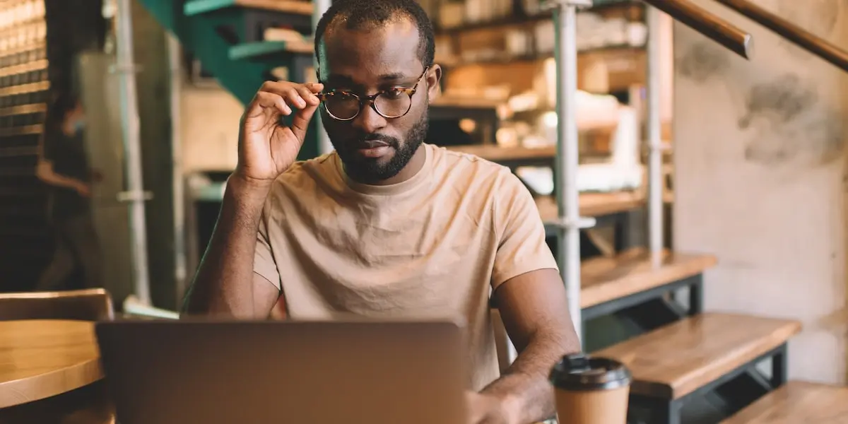 A web developer works at his laptop in a modern coworking space.