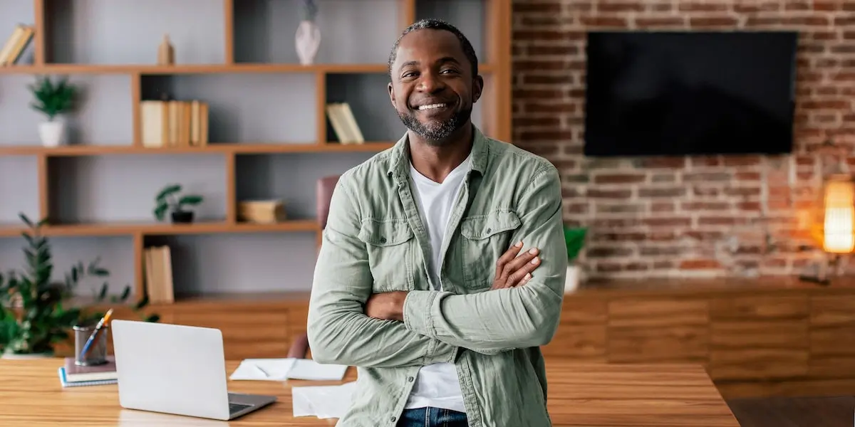 An agile product management expert stands by his desk and computer in his home office.