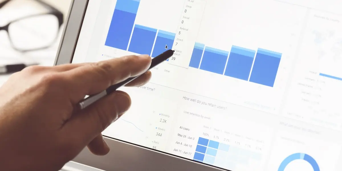 Close up of a screen showing digital marketing analytics and a hand with a stylus pointing to a graph on the page