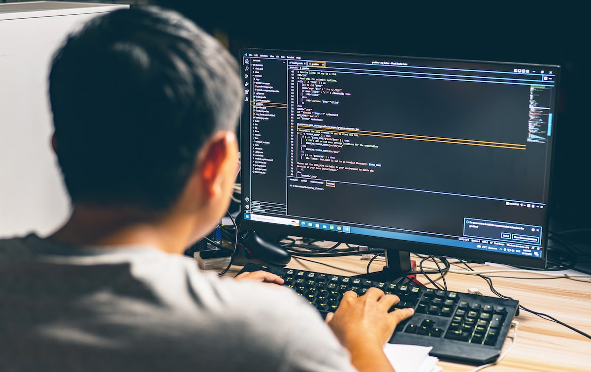 A software engineer writes simple code on a desktop screen to make debugging it easier.