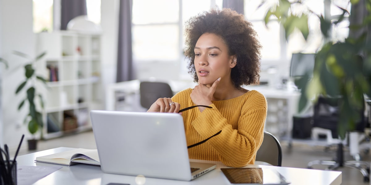 A woman working one of the jobs of the future sits at her laptop in a bright home office.