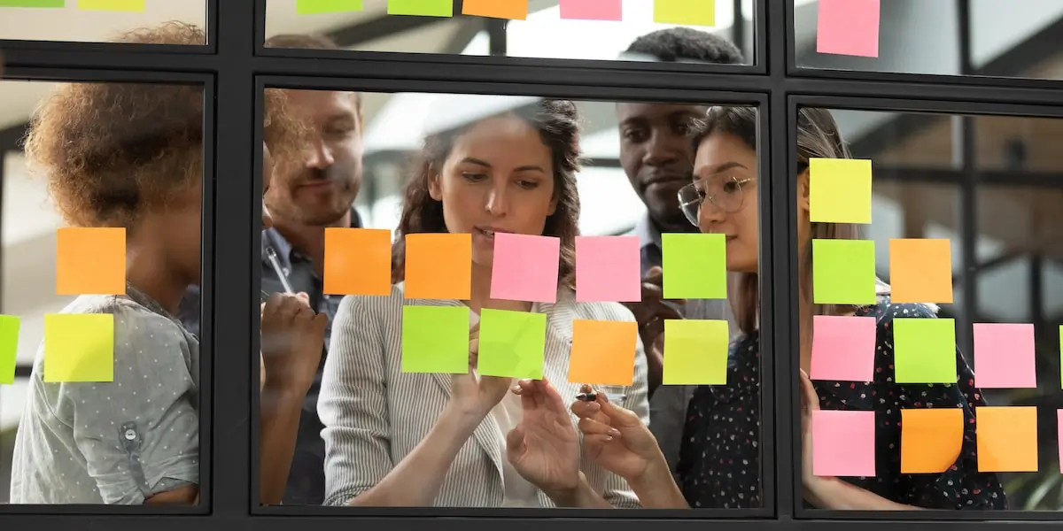 A product team using sticky notes on a window in a kanban vs scrum configuration.