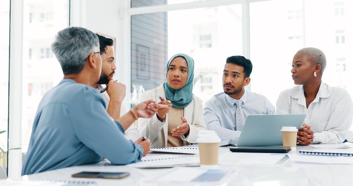A woman in a headscarf leads a sprint review meeting.