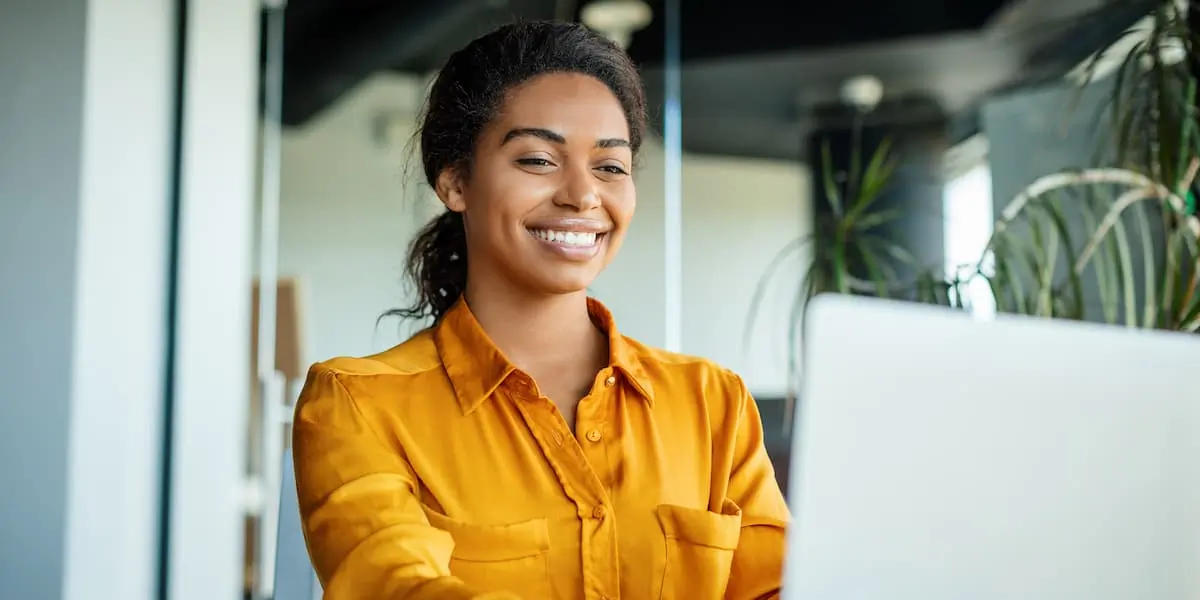 Young smiling woman sits at computer writing a career change cover letter
