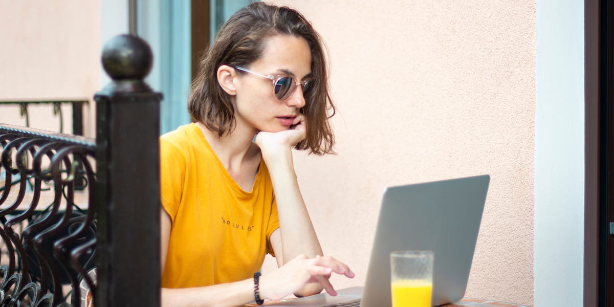 A woman coding using AI programming tools on her laptop outside.