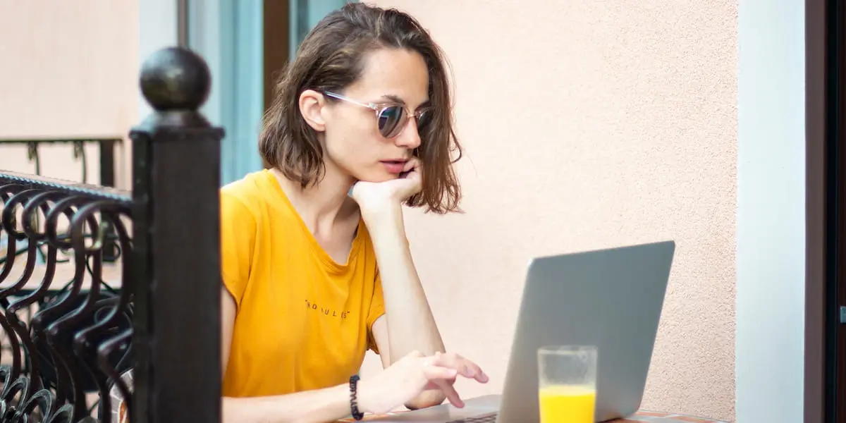 A woman coding using AI programming tools on her laptop outside.