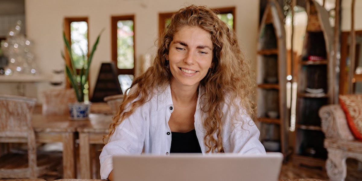 A young woman with curly hair looking at digital marketing reddit posts on her laptop