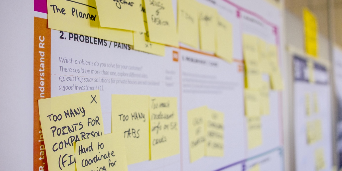 Sticky notes all over a customer journey map on a wall, detailing user pain points
