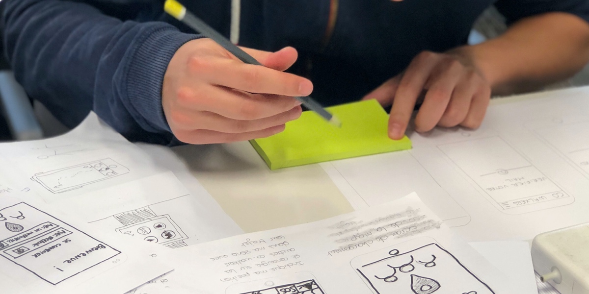 Close up of a UX writer's hands, creating paper prototypes for an app