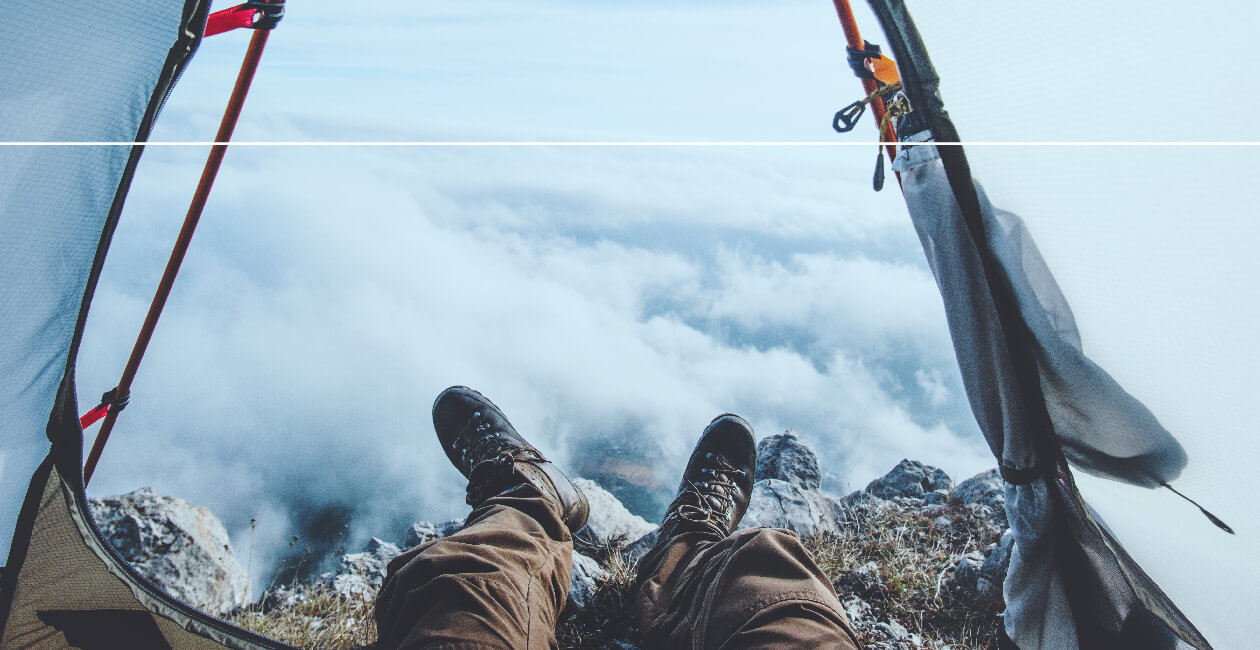 Feet poking out of a tent, sitting at the top of a mountain